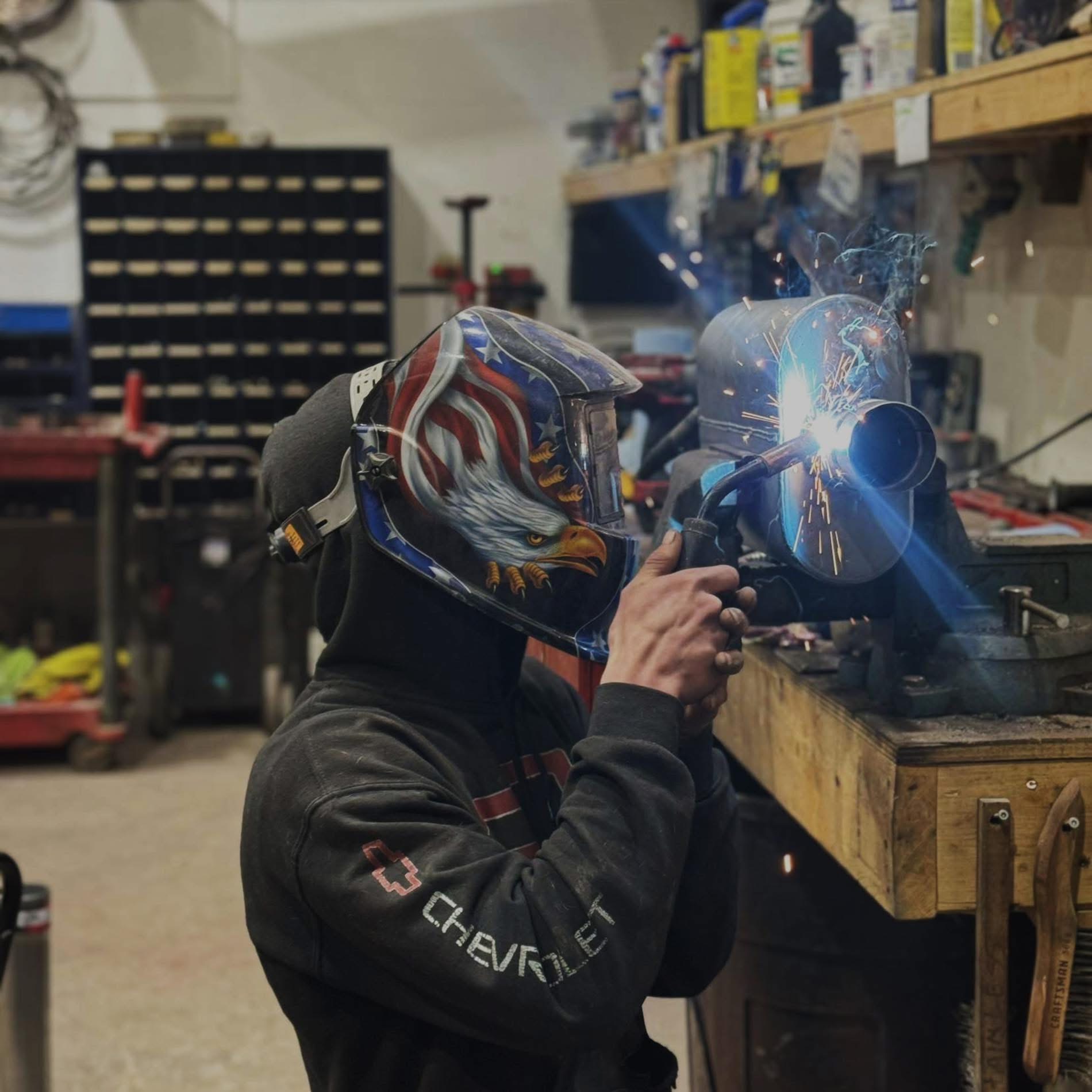 Javen, owner of Javens AutoWorks, welding an exhaust part at the shop workbench