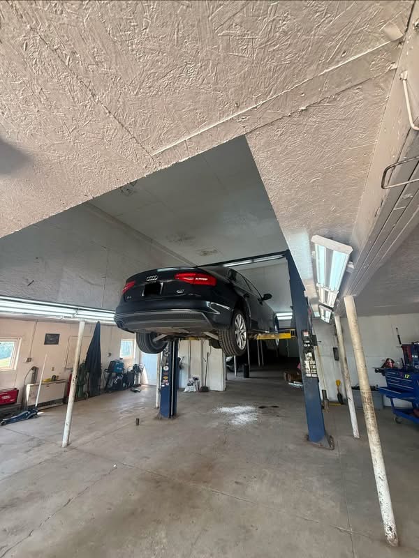 A black Audi raised on a two-post lift inside the Javens AutoWorks shop in Wales, Maine